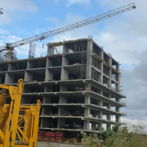 Phoenix Rising Eko Atlantic City multi-storey luxury building under construction with tower crane, exposed concrete floors, and vehicles on lower levels