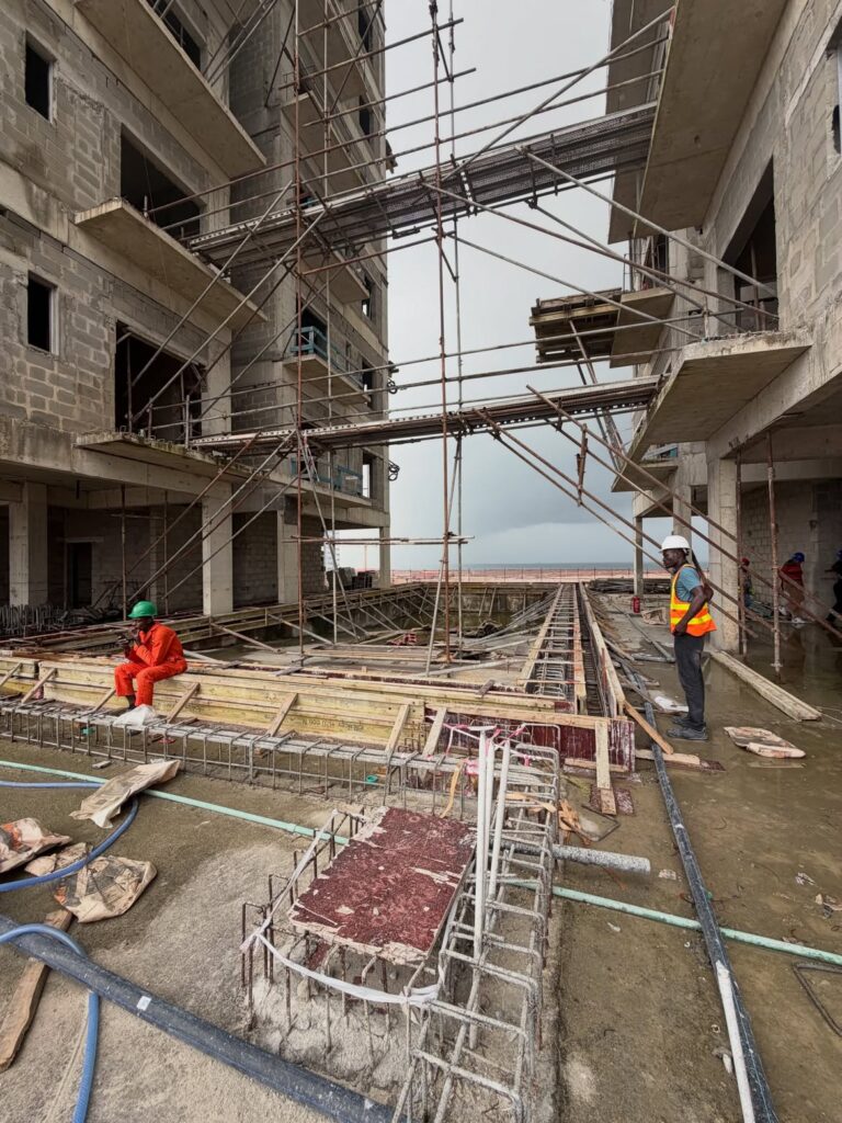 Paramount Twin Towers Oniru active construction site between the twin towers showing scaffolding rebar workers and ocean view in background